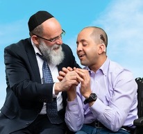 Rabbi and man with disabilities holding hands